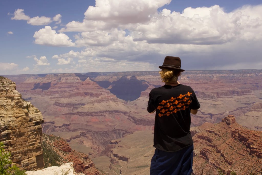 Homme qui prend en photo le Grand Canyon devant lui